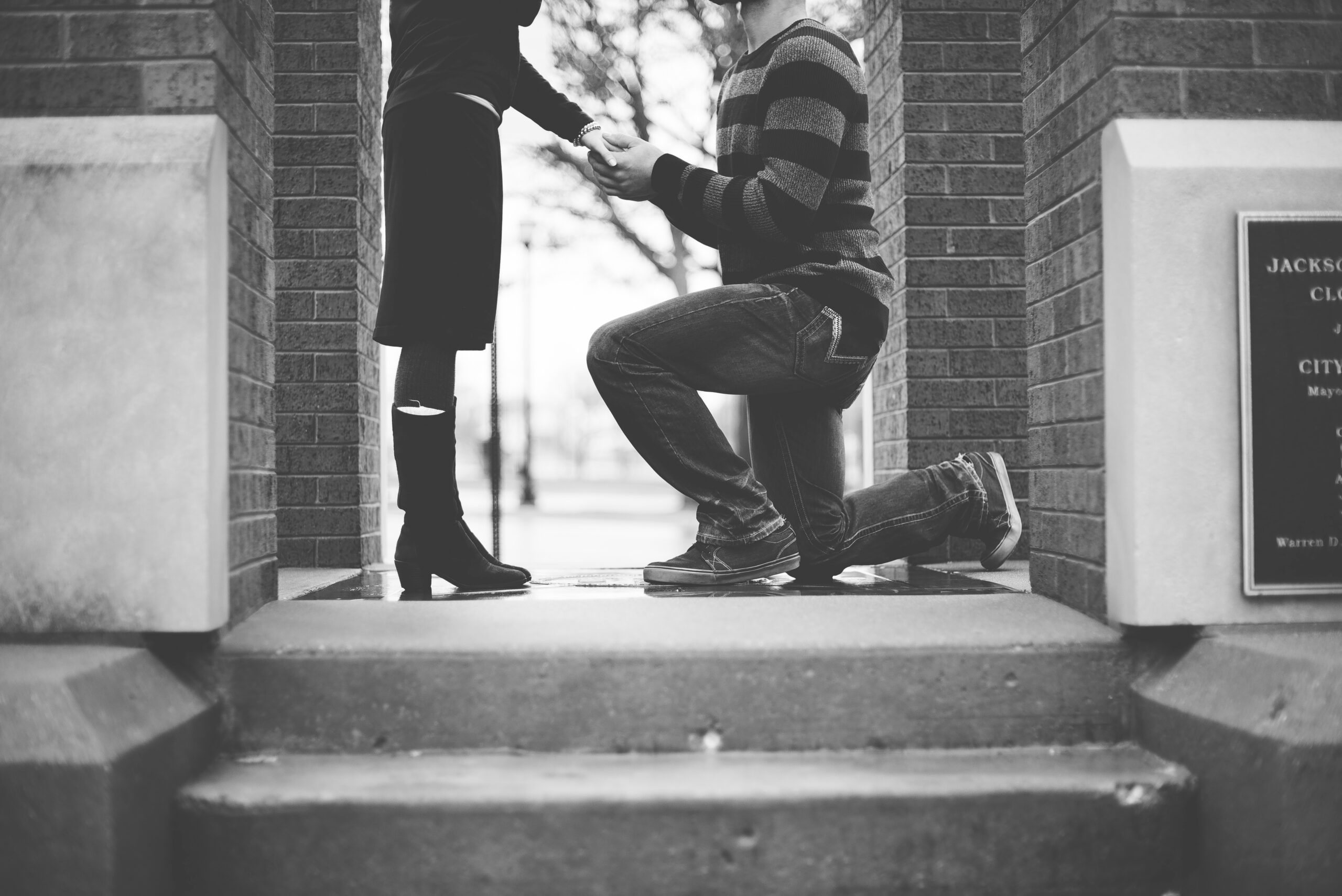 A man proposing to a woman on one knee on stairs