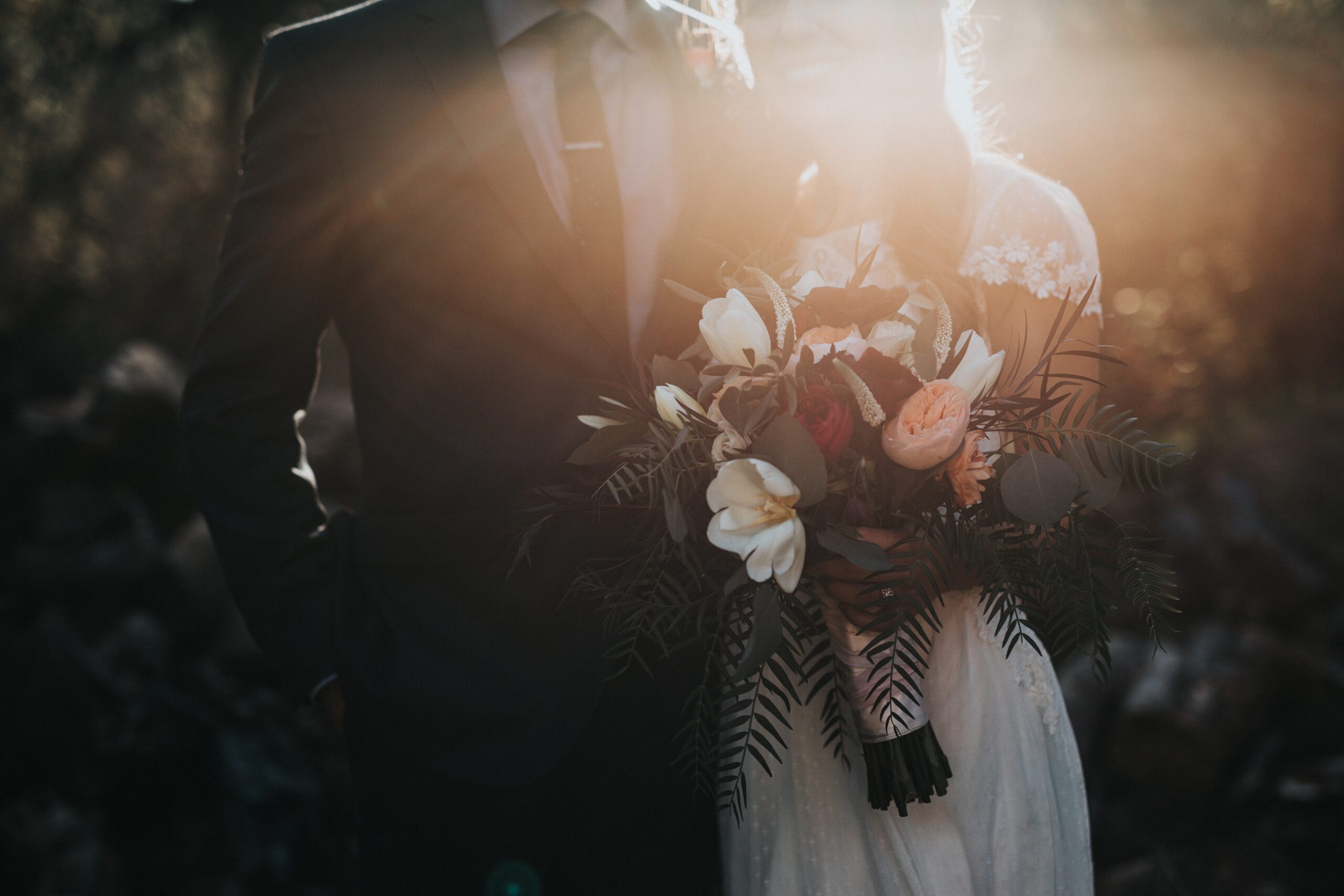 A bride and groom standing in front of a sunset