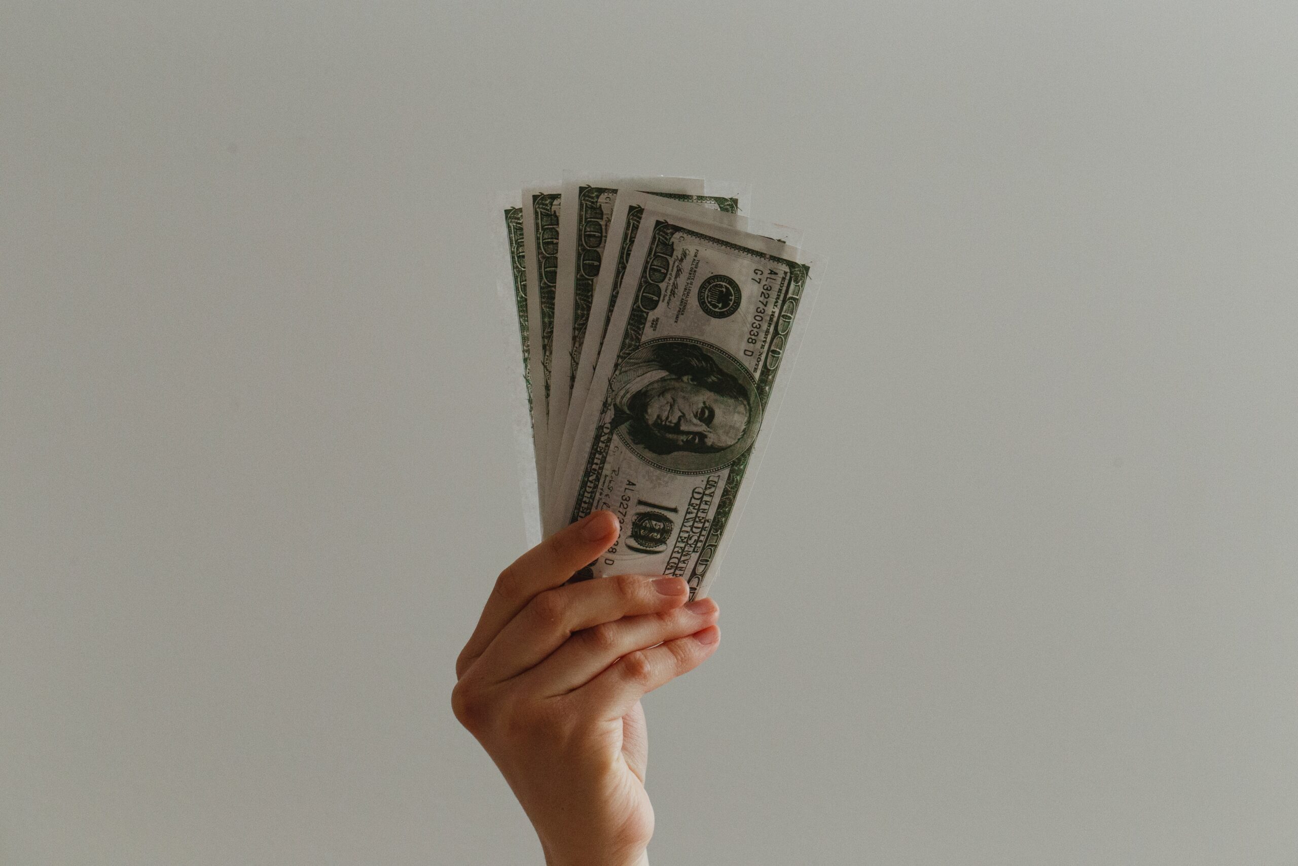 Hand holding up 100 dollar bills